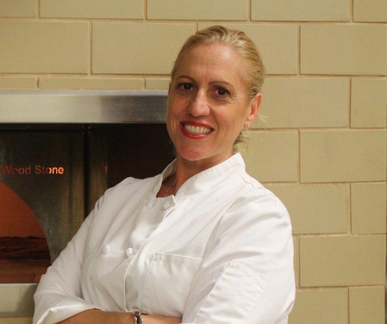 A woman in white shirt standing next to a brick wall.